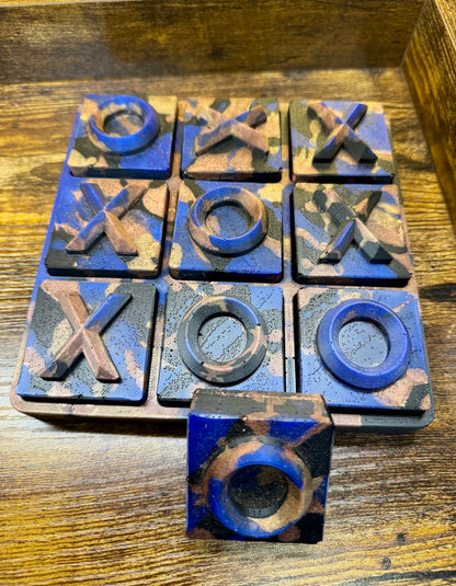 Resin tic-tac-toe game set with blue and brown pieces on a wooden surface