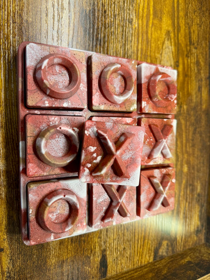 Red resin “stone like” tic-tac-toe board with Xs and Os on a wooden surface