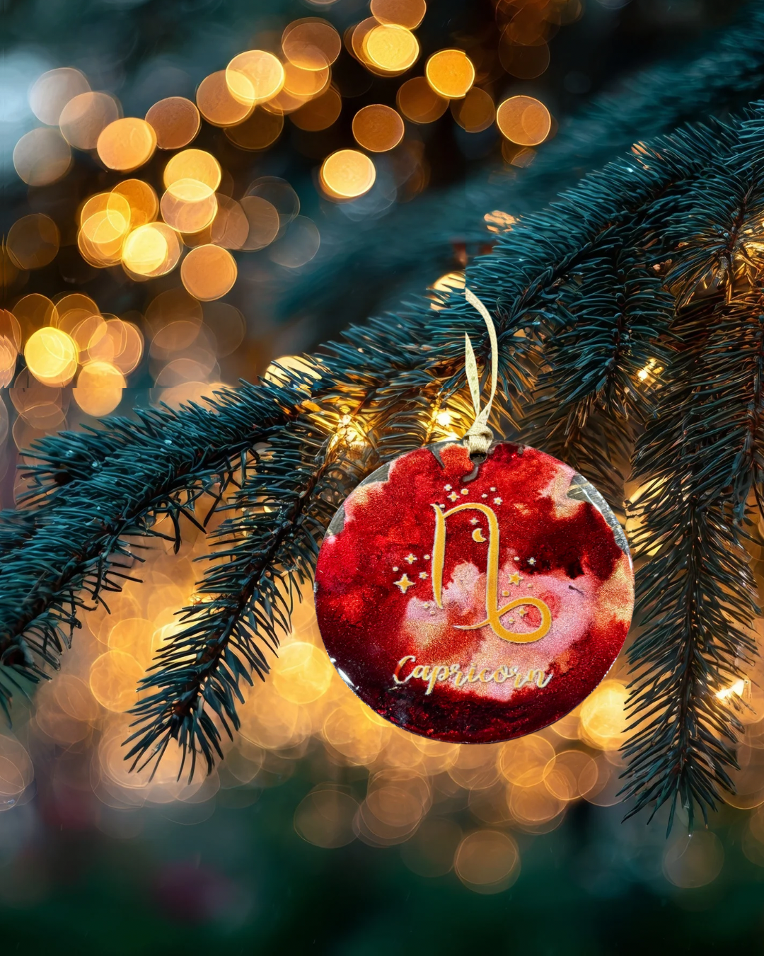 Decorative ornament with 'Capricorn' on a Christmas tree branch with lights in the background