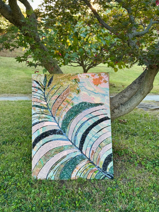 Colorful abstract leaf painting and resin art on grass with trees in the background
