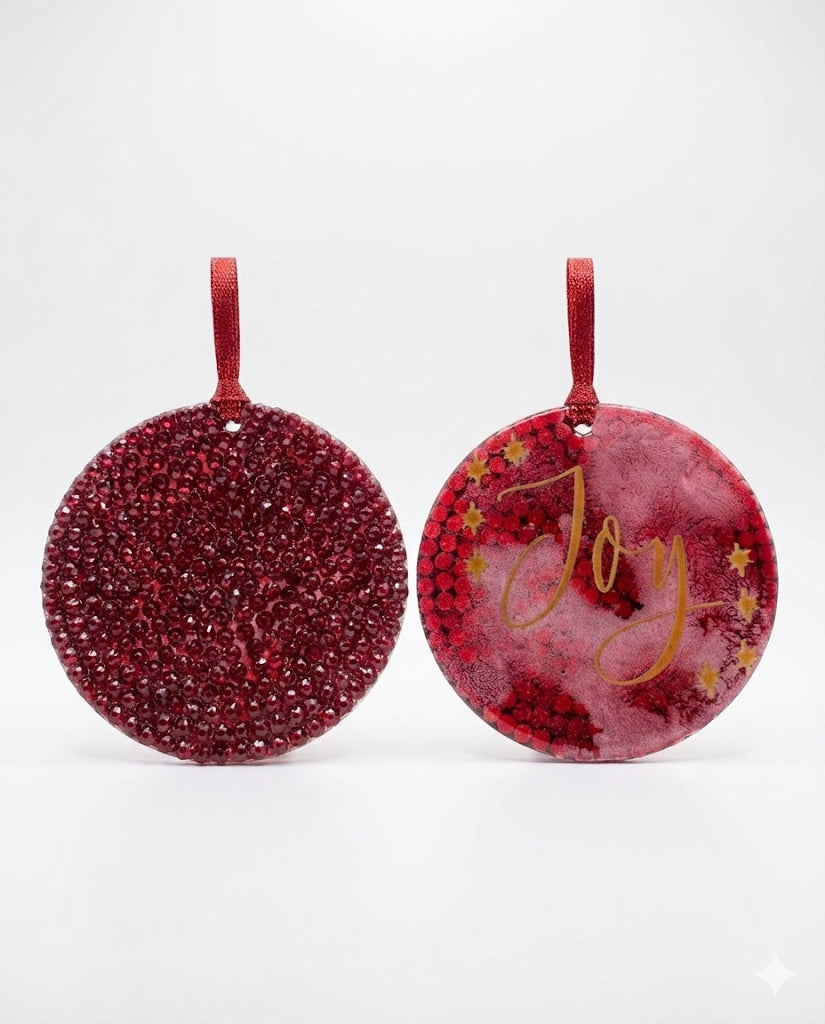 Two red glittery Christmas ornaments with 'Joy' text on a white background